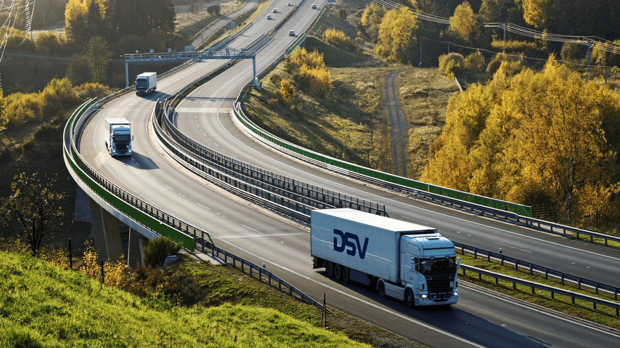 DSV-trailer kjører på motorvei med oransje og grønn vekst på begge sider.